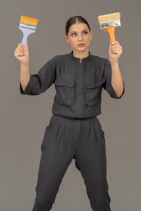 Young woman holding up paint brushes