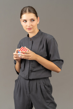 Vista di tre quarti di una giovane donna in tuta che tiene il cubo di rubik
