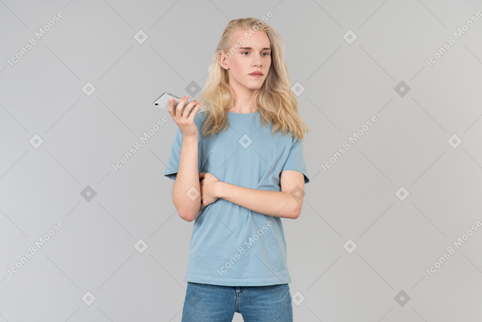 Pensive young guy with long hair holding smartphone