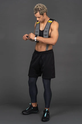 Three-quarter view of a shirtless afro man adjusting his vest