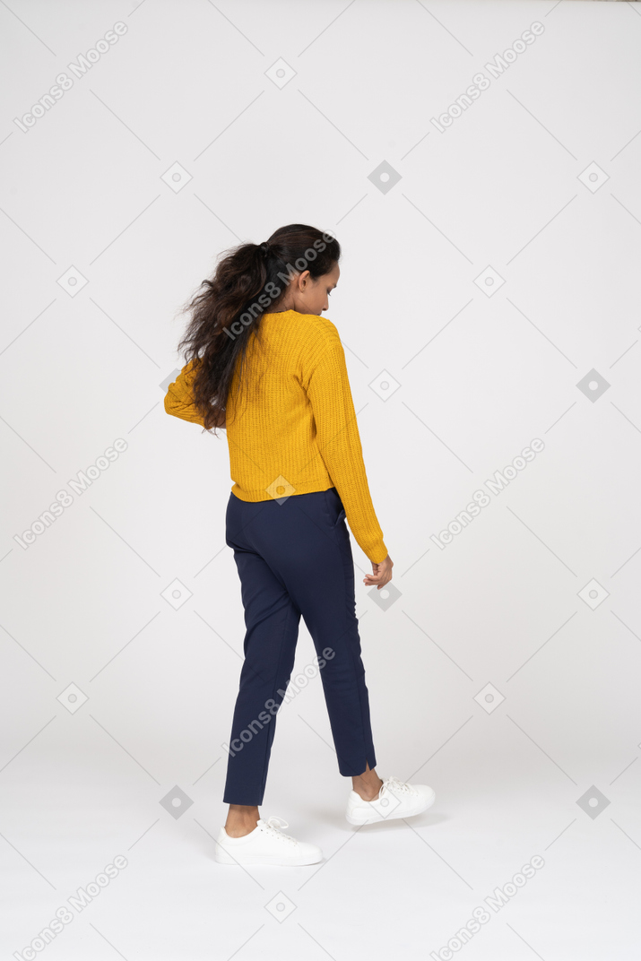 歩いて見下ろしているカジュアルな服装の女の子の背面図