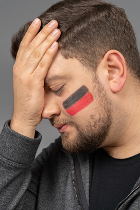 Front view of a puzzled male football fan touching head