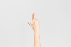Weibliche hand, die gewehr mit den fingern zeigt