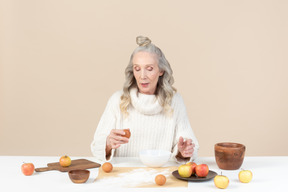 Elegante donna anziana che cucina un pasticcino alle mele
