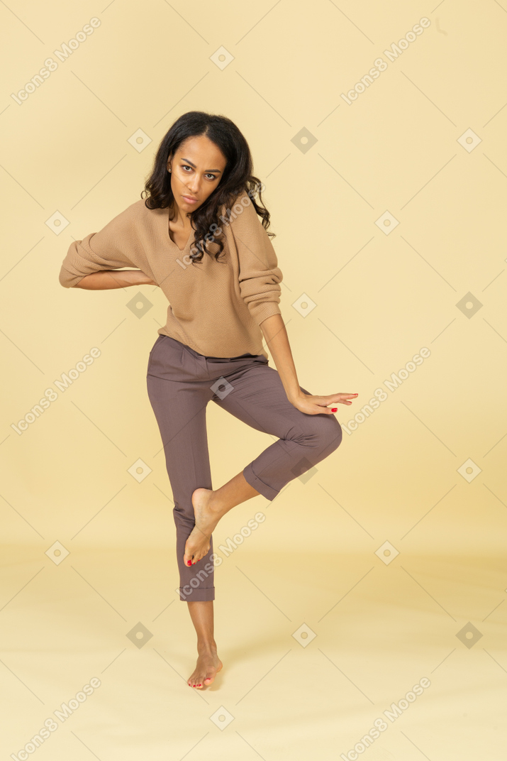 Вид спереди темнокожей молодой женщины, опирающейся на ногу