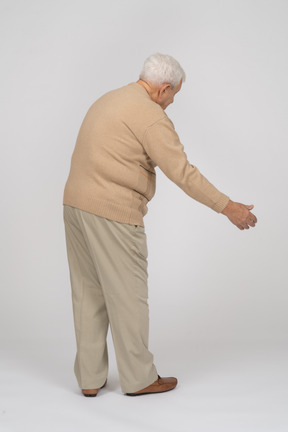 Side view of an old man in casual clothes giving a hand for shake