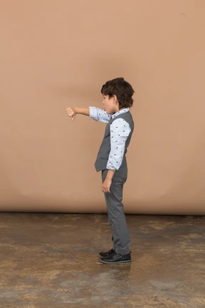 Side view of a boy in grey suit showing thumb down