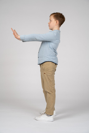Vista lateral de um menino de pé com os braços estendidos