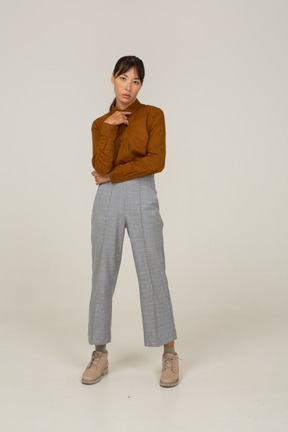Vista frontal de una mujer asiática joven pensativa en calzones y blusa