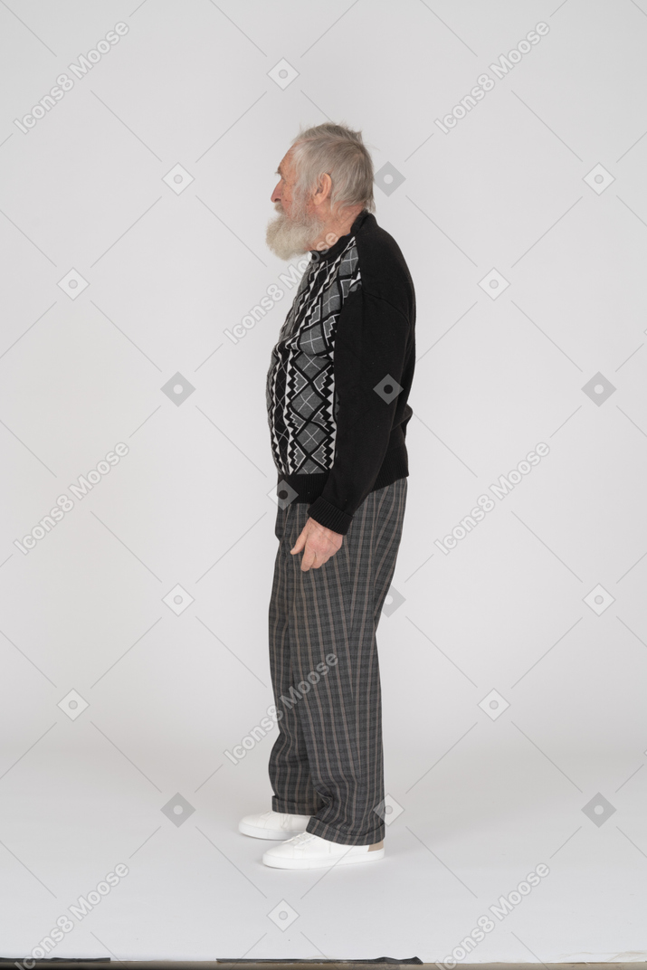 Side view of bearded old man standing with arms at side