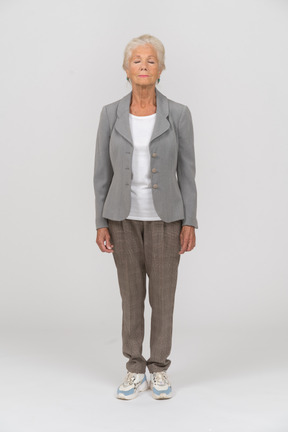 Front view of an old woman in suit standing with closed eyes