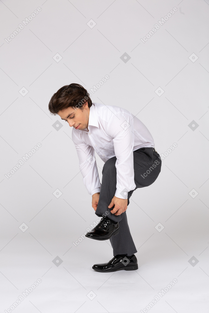 Homem se abaixando e ajustando as calças