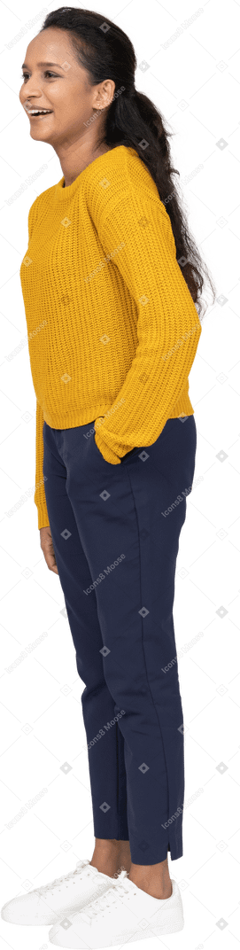 Side view of a happy girl in casual clothes posing with hand in pocket