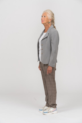 Old woman in grey jacket standing in profile