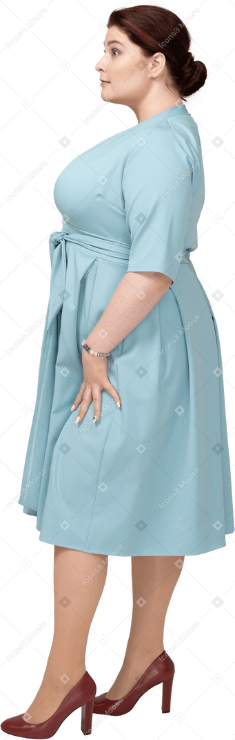Frau im blauen kleid steht im profil