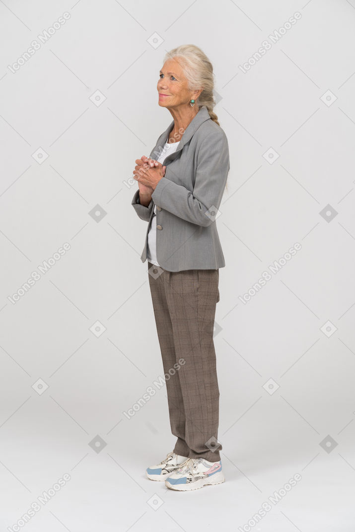 Senhora idosa de terno em pé de perfil