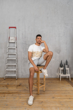 Relaxed young man sitting on stool