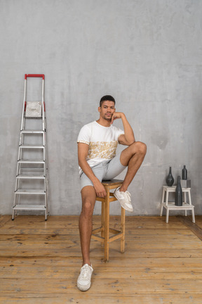 Jeune homme détendu assis sur un tabouret