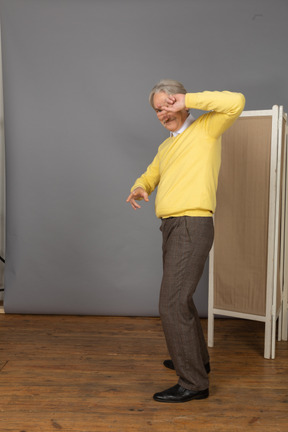 Vista lateral de un anciano bailando fresco escondiendo su rostro