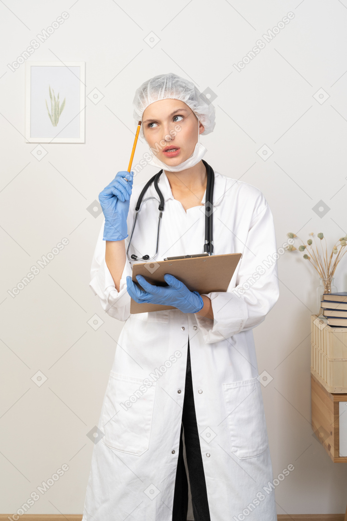 Front view of a puzzled young female doctor making notes on her tablet