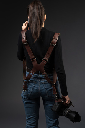 Female photographer standing backwards to camera while talking by phone