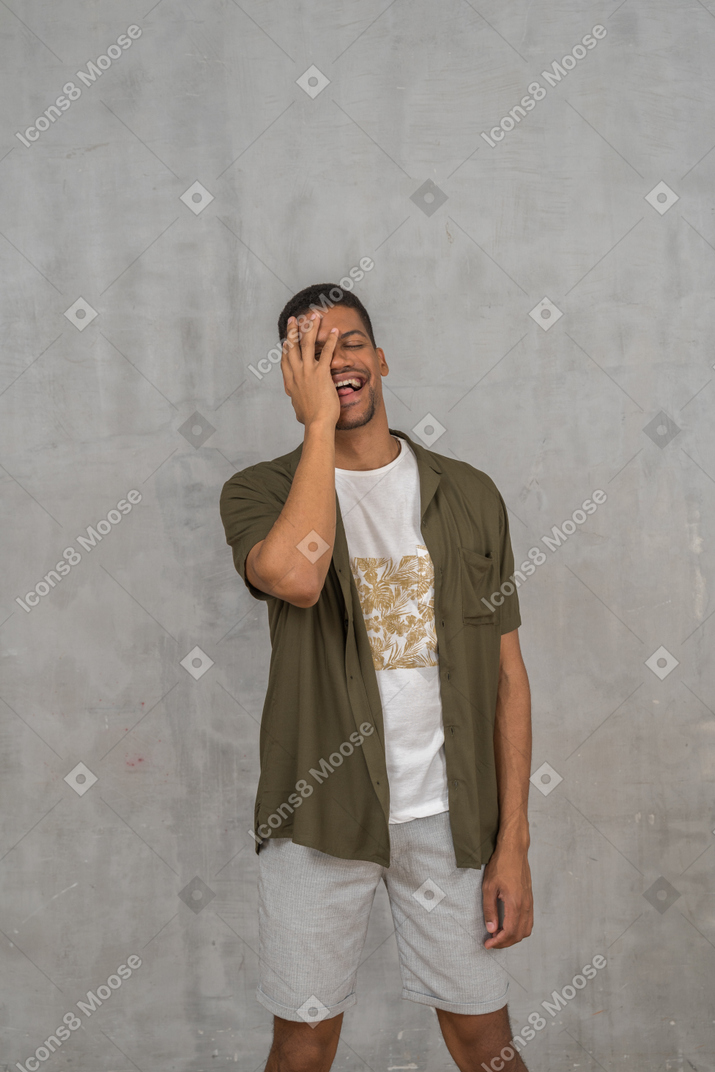Laughing man covering his face with hand