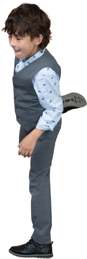 Vista laterale di un ragazzo in abito grigio in piedi su una gamba