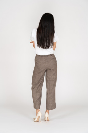 Back view of a wondering young lady in breeches and t-shirt raising her hands