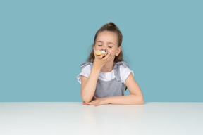 Jolie petite fille dégustant un beignet