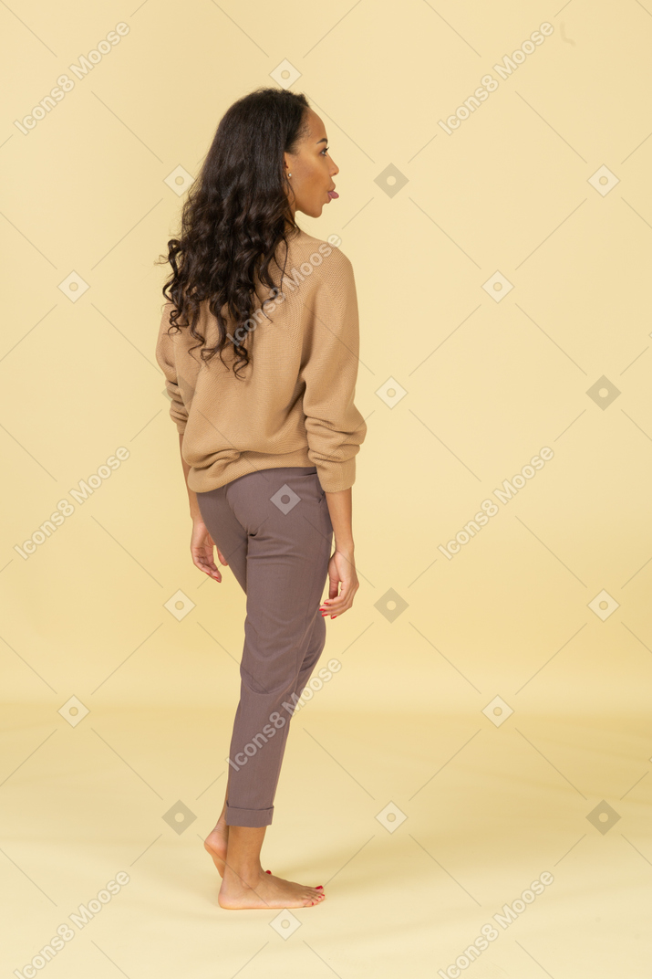 Vista posterior de una mujer joven en ropa casual mostrando lengua
