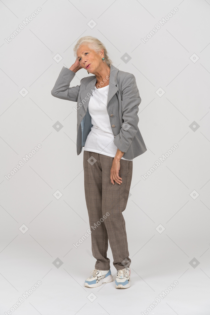 Vista frontal de uma senhora idosa de terno tocando seu cabelo