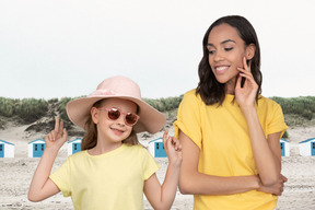 A woman standing next to a little girl on a beach