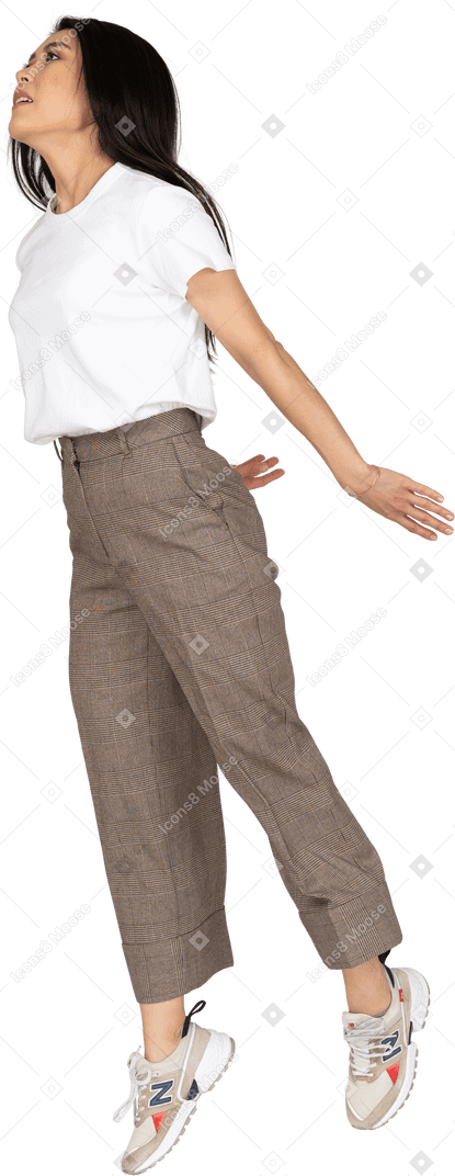 Vista di tre quarti di una giovane donna che salta in calzoni e t-shirt