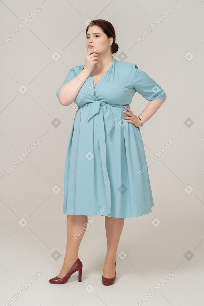 Женщина в синем платье думает о чем-то, вид спереди
