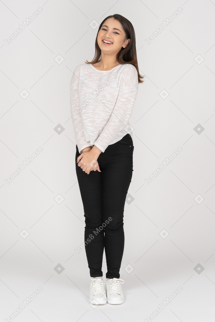 Cheerful laughing young woman holding hands together and looking at camera