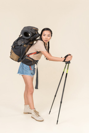 Tired looking hiker woman walking using trekking poles