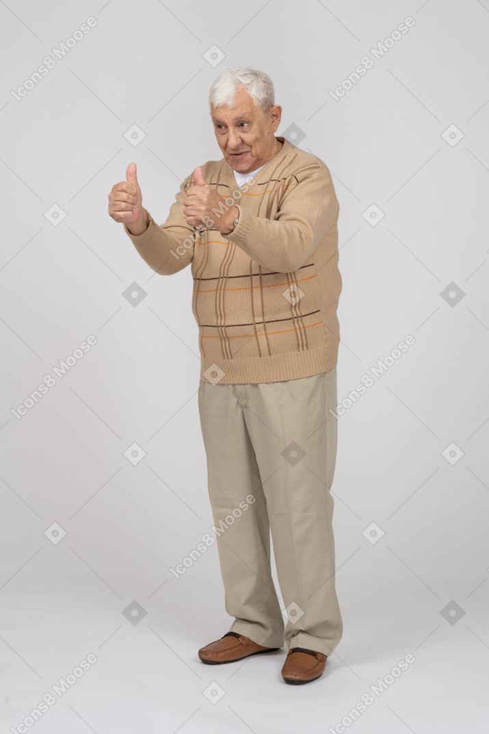 Vue de face d'un vieil homme heureux dans des vêtements décontractés montrant les pouces vers le haut