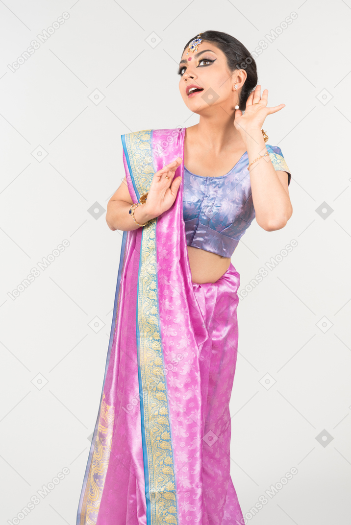 Giovane donna indiana in sari viola in piedi con le mani giunte