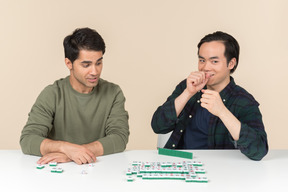 Amigos interraciais sentado à mesa e jogando scramble