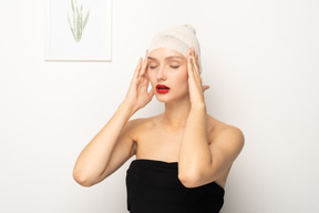 Young woman with bandaged head touching temples