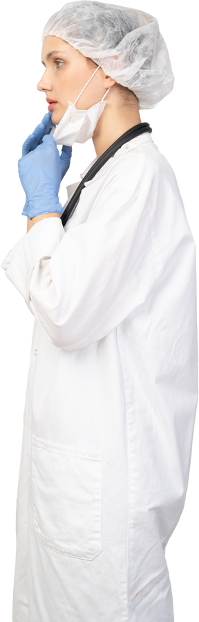 Vista lateral de uma jovem médica colocando uma máscara
