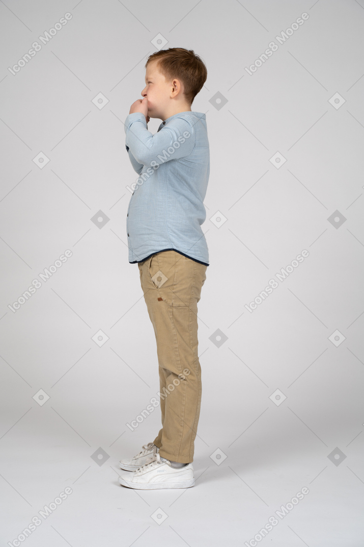 Side view of a cute boy putting fingers in mouth