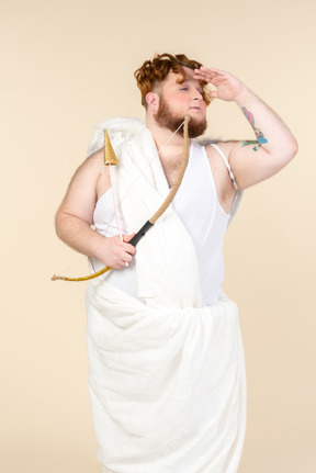 Young big man dressed as a cupid holding bow and arrow