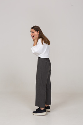 Side view of an excited young lady in office clothing touching face
