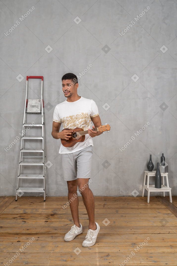 Three-quarter view of a man playing ukulele nonchalantly