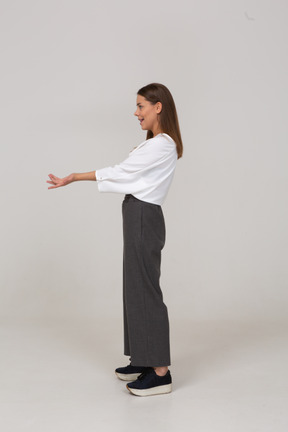Vista lateral de una joven en ropa de oficina extendiendo sus brazos