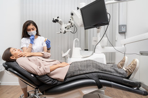 Comprimento total de uma dentista mostrando protótipo de dentes para paciente em um gabinete de hospital