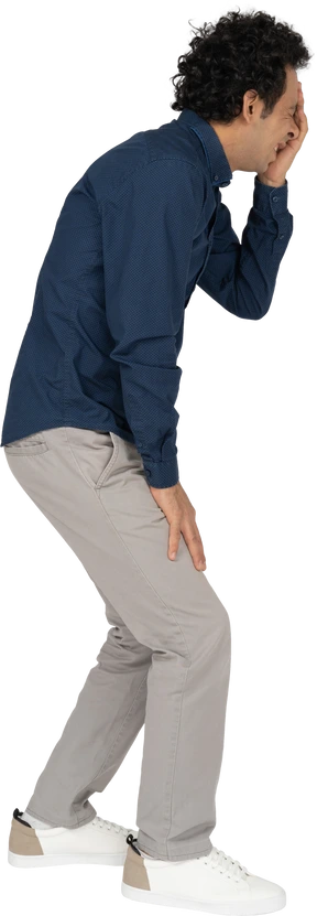 Side view of a man in casual clothes covering eye with hand