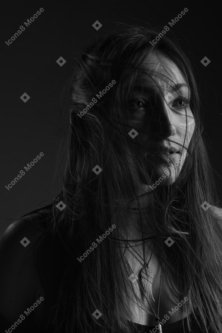 Retrato noir de três quartos de uma jovem mulher com arte facial étnica e cabelo bagunçado
