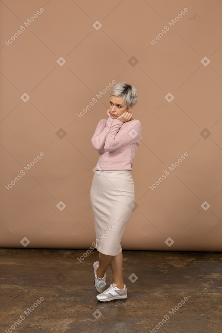 Вид спереди симпатичной женщины в повседневной одежде, касающейся ее лица руками